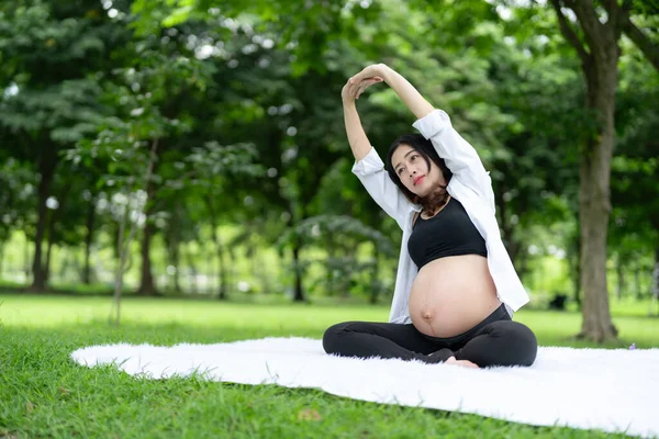 亚洲孕妇在公园放松运动的肖像 免版税图库图片