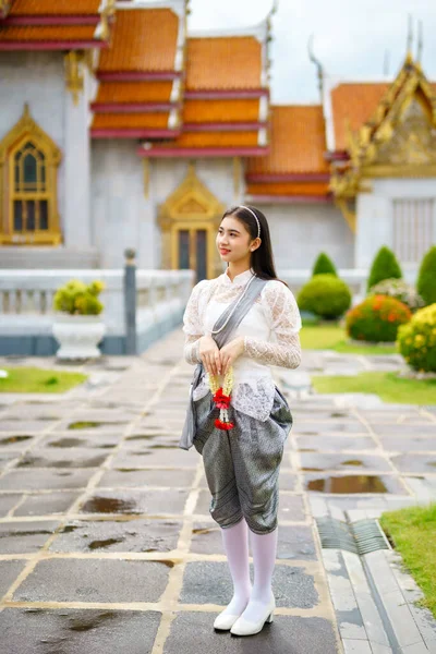 在泰国一座根据泰国艺术建造的庙宇中穿着泰国拉达那科辛民族服装的年轻漂亮女子的画像 图库照片