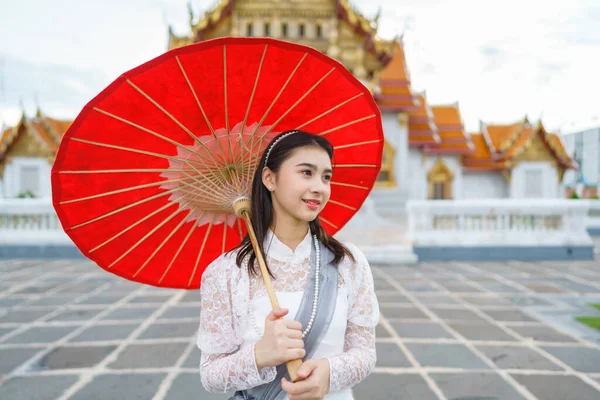 在泰国一座根据泰国艺术建造的庙宇中穿着泰国拉达那科辛民族服装的年轻漂亮女子的画像 图库图片