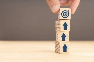 İş hedefi ve objektif hedef kavramı. Yığılmış blokların üzerinde hedef simgesi ve okları olan bir küp tutuyorum. Boşluğu kopyala