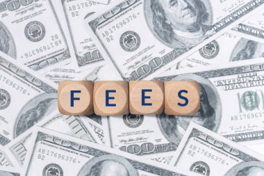 FEES word on wooden blocks and US dollar bills background clipart