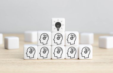 Beyin Fırtınası Takımı, yaratıcı fikir ya da yenilikçi fikir. Piramit merdiven şeklinde düzenlenmiş dişli başlıklı küp blokları ve en üstte bir ampul simgesi