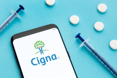 Galicia, Spain; June 8, 2021 : Cigna logo on Smart phone screen pills and syringe on blue background
