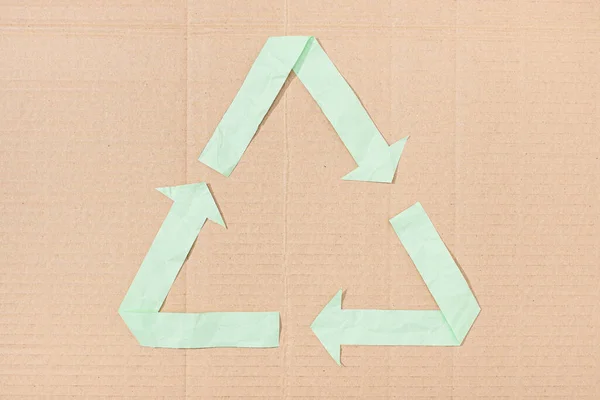 Recycle symbol made of green paper cut on cardboard background texture