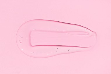 Liquid gel or beauty serum texture isolated on pink background. Transparent cosmetic skincare product. Close up