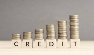 Credit increasing concept. Text word on wooden blocks with coins stacked in increasing stacks. Copy space