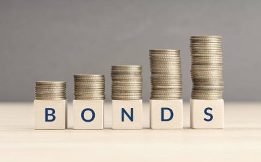 Bonds increasing concept. Text word on wooden blocks with coins stacked in increasing stacks. Copy space