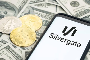 Galicia, Spain; january 28, 2022: Silvergate financial services company logo on Smartphone screen, dollar banknotes and crypto coins on table clipart