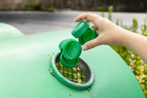 Close up of a Hand throwing plastic caps into a urban recycling bin