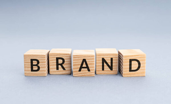 Брендовое слово на деревянных блоках. Серый фон с копировальным пространством