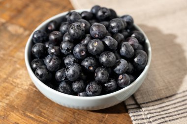 Taze olgun yaban mersinlerini bir kaseye koyup sağlıklı ve lezzetli bir hayat yaratıyor.