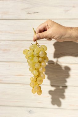 Beyaz ahşap arka planda izole edilmiş olgun beyaz üzümler.