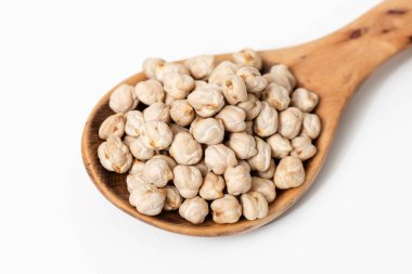Beyaz arkaplanda çiğ nohut bulunan ahşap kaşığın yakın çekimi