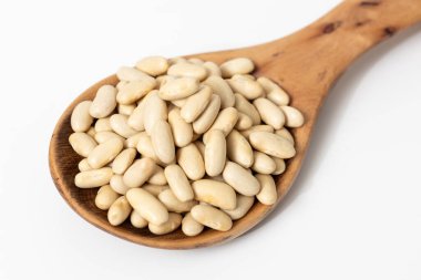 Beyaz zemin üzerinde çiğ cannellini fasulyesi olan tahta bir kaşığın yakın çekimi.