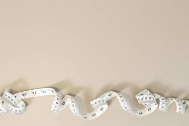 Beyaz mezura bej arka planda bir sınır oluşturuyor. Kilo kaybı, diyet ve terzilik için ideal. Boşluğu kopyala