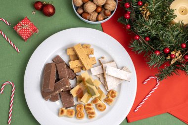 Geleneksel İspanyol noel tatlıları, turon, çikolata ve badem ezmesi de dahil olmak üzere, festival masasında bir tabağa yerleştirilmiş.