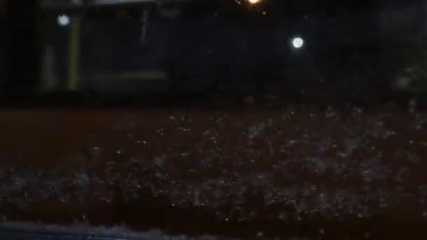 汽车挡风玻璃的内景 雨夹雪落在窗上 透过玻璃窗上的雨 模糊了视觉 金色的光水滴 透明玻璃 — 图库视频影像