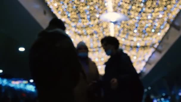 圣诞假期装饰 新年快乐 人们在明亮的蓝色和黄色闪烁着柔和聚光灯的背景下交谈 聚焦功能 镜头的Bokeh 手电筒 — 图库视频影像