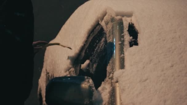 开车前用刮冰刀把车的侧窗从雪地上擦干净 一个人把冰块从车窗上移开 在寒冷的冬夜 一个男人在清扫一辆汽车 — 图库视频影像