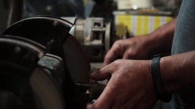 Elektrikli değirmen çarkında bir bıçağı bilemek, makine elektrikli öğütücüde bir kınkanatlıyı bilemek, dönen taşta elle bilemek, yakın plan.