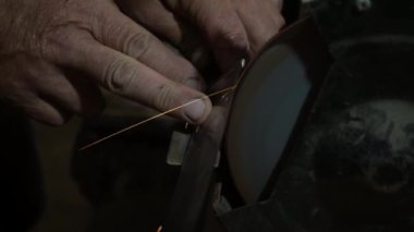 Elektrikli değirmen çarkında bir bıçağı bilemek, makine elektrikli öğütücüde bir kınkanatlıyı bilemek, dönen taşta elle bilemek, yakın plan.