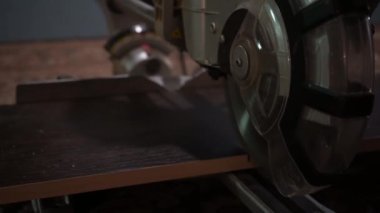 Erkek marangoz, bir marangoz atölyesinde dairesel testere ile tahtayı kesiyor. Dairesel testere. Marangoz tahta için testere kullanıyor.