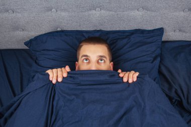 Yukarı bak. Battaniyenin arkasına saklanan yakışıklı genç bir adam yana bakıyor. Bakışların yönü farklı yönlerde