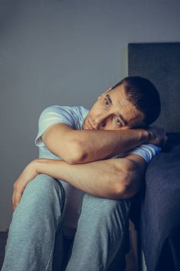 30 'lu ve 40' lı yaşlarda yakışıklı bir adamın dramatik bir hayat tarzı portresi. Üzüntülü bir şekilde yatakta oturuyor ve depresyondan muzdarip. Çekici depresif ve üzgün bir adam.