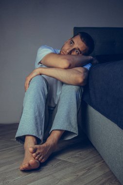 30 'lu ve 40' lı yaşlarda yakışıklı bir adamın dramatik bir hayat tarzı portresi. Üzüntülü bir şekilde yatakta oturuyor ve depresyondan muzdarip. Çekici depresif ve üzgün bir adam.
