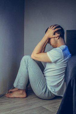 30 'lu ve 40' lı yaşlarda yakışıklı bir adamın dramatik bir hayat tarzı portresi. Üzüntülü bir şekilde yatakta oturuyor ve depresyondan muzdarip. Çekici depresif ve üzgün bir adam.