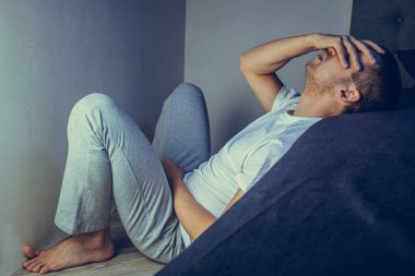 30 'lu ve 40' lı yaşlarda yakışıklı bir adamın dramatik bir hayat tarzı portresi. Üzüntülü bir şekilde yatakta oturuyor ve depresyondan muzdarip. Çekici depresif ve üzgün bir adam.