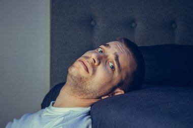 30 'lu ve 40' lı yaşlarda yakışıklı bir adamın dramatik bir hayat tarzı portresi. Üzüntülü bir şekilde yatakta oturuyor ve depresyondan muzdarip. Çekici depresif ve üzgün bir adam.