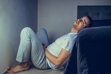 30 'lu ve 40' lı yaşlarda yakışıklı bir adamın dramatik bir hayat tarzı portresi. Üzüntülü bir şekilde yatakta oturuyor ve depresyondan muzdarip. Çekici depresif ve üzgün bir adam.