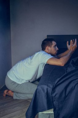 30 'lu ve 40' lı yaşlarda yakışıklı bir adamın dramatik bir hayat tarzı portresi. Üzüntülü bir şekilde yatakta oturuyor ve depresyondan muzdarip. Çekici depresif ve üzgün bir adam.