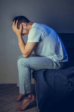 Morali bozuk bir adam yerde oturuyor, başı öne eğik ve duvara yaslanıyor. Hayal kırıklığına uğramış duygularla. Zihinsel bozukluk kavramı. Şizofreni, psikoz, korku