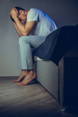 30 'lu ve 40' lı yaşlarda yakışıklı bir adamın dramatik bir hayat tarzı portresi. Üzüntülü bir şekilde yatakta oturuyor ve depresyondan muzdarip. Çekici depresif ve üzgün bir adam.