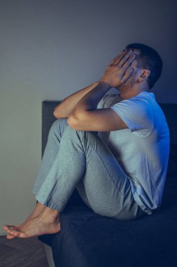 30 'lu ve 40' lı yaşlarda yakışıklı bir adamın dramatik bir hayat tarzı portresi. Üzüntülü bir şekilde yatakta oturuyor ve depresyondan muzdarip. Çekici depresif ve üzgün bir adam.