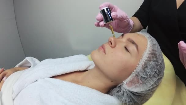 美容师把血清涂在一个漂亮姑娘的脸上 皮肤湿透了 漂亮的女孩在美容院 美容师把奶油涂在姑娘们的脸上 — 图库视频影像