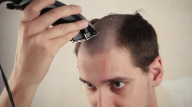 Evde, bir adam aynanın önünde kel noktasını tıraş eder. saç kaybı sorunu