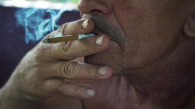 Bir adam iş arasında sigara içer. Yakın plan. Çok duman var. Sigara içmek sağlığa zararlıdır. Kötü alışkanlık kavramı