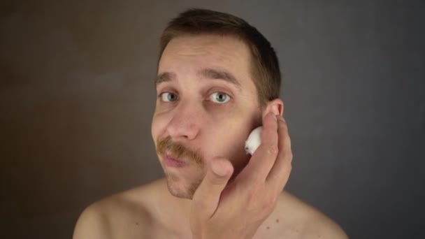 Bonito Sorrindo Sem Barbear Jovem Aplicando Espuma Barbear Hidratante Rosto — Vídeo de Stock