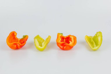 Yarım yeşil ve kırmızı dolmalık biberler beyaz arka planda izole edilmiş. Hatlar kesiliyor. Yukarıdan görüntüle