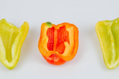 Yarım yeşil ve kırmızı dolmalık biberler beyaz arka planda izole edilmiş. Hatlar kesiliyor. Yukarıdan görüntüle