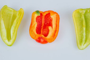 Yarım yeşil ve kırmızı dolmalık biberler beyaz arka planda izole edilmiş. Hatlar kesiliyor. Yukarıdan görüntüle