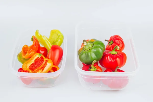 Mixed organic red, green and yellow peppers in a container. Storage of vegetables. Organization of space in the kitchen