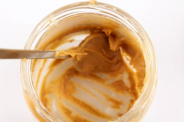 Peanut butter in an open jar. Empty peanut butter container. The last spoonful of delicious pasta snacks