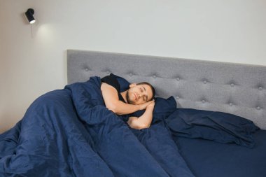 Geceleri yatak odasındaki yatakta rahat uyuyan yakışıklı bir delikanlının üst görüntüsü. Bekar odası. Derin uyku.