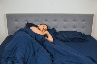 Geceleri yatak odasındaki yatakta rahat uyuyan yakışıklı bir delikanlının üst görüntüsü. Bekar odası. Derin uyku.