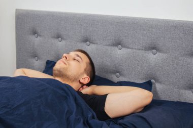 Geceleri yatak odasında, yatakta rahat uyuyan yakışıklı bir delikanlının en iyi görüntüsü. Farklı pozisyonlarda uyu. Bekar odası. Derin uyku.
