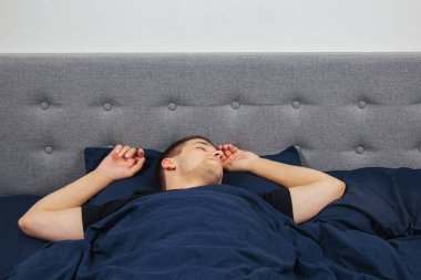 Geceleri yatak odasında, yatakta rahat uyuyan yakışıklı bir delikanlının en iyi görüntüsü. Farklı pozisyonlarda uyu. Bekar odası. Derin uyku.